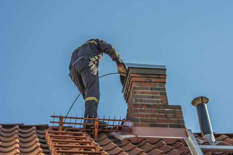 Modern Chimney Sweep on a roof, cleaning a chimney